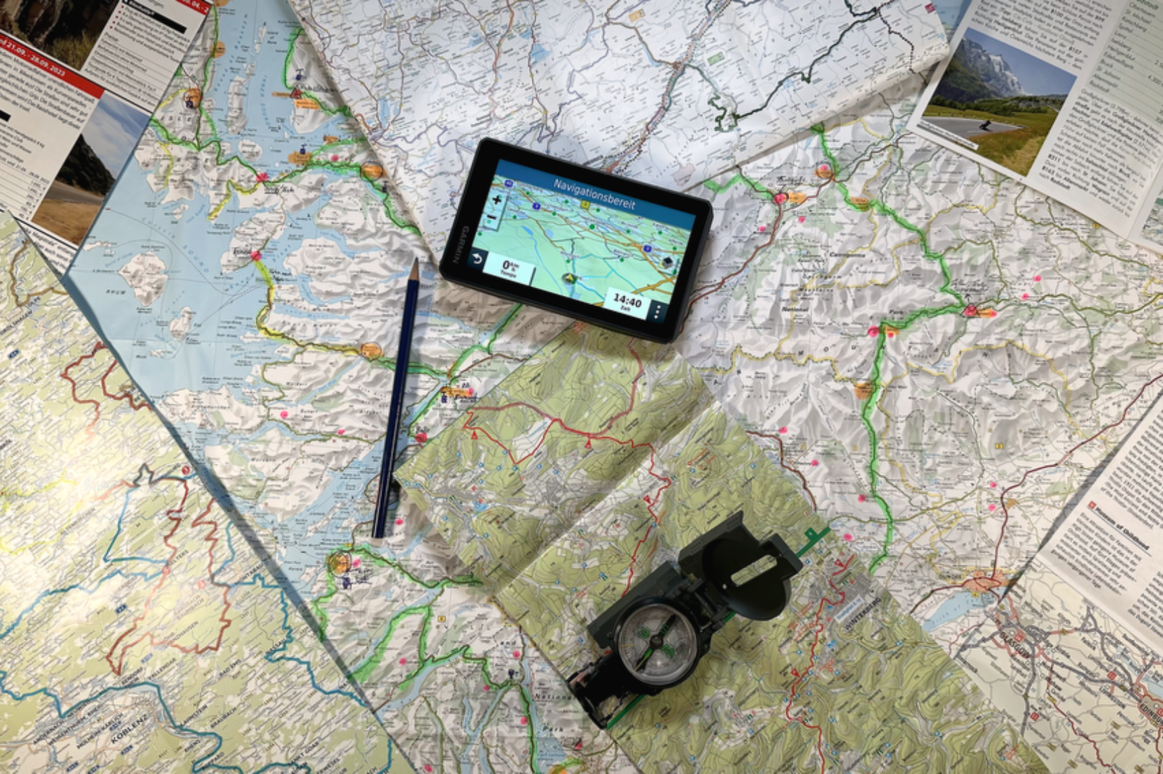 Reisevorbereitung Karten, ein Navigationsgerät und ein Kompass auf einem Tisch, vorbereitet für eine Reise.